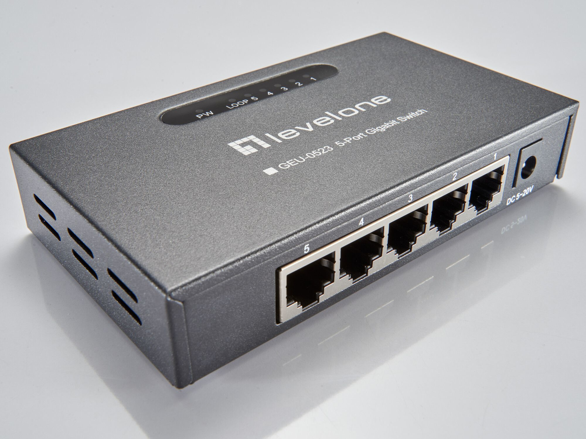 Uno switch Gigabit LevelOne grigio a 5 porte, con cinque porte, una porta di alimentazione e spie luminose, su una superficie bianca.