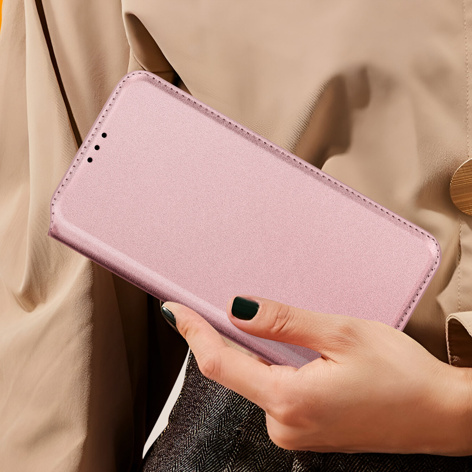 Donna che tiene in mano una custodia rosa per telefono. Telefono dentro, vista laterale. Sfondo beige.