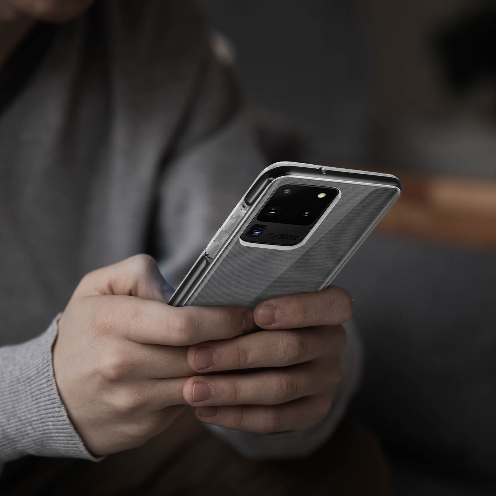 Una persona tiene in mano un telefono con custodia trasparente, con logo Samsung visibile.