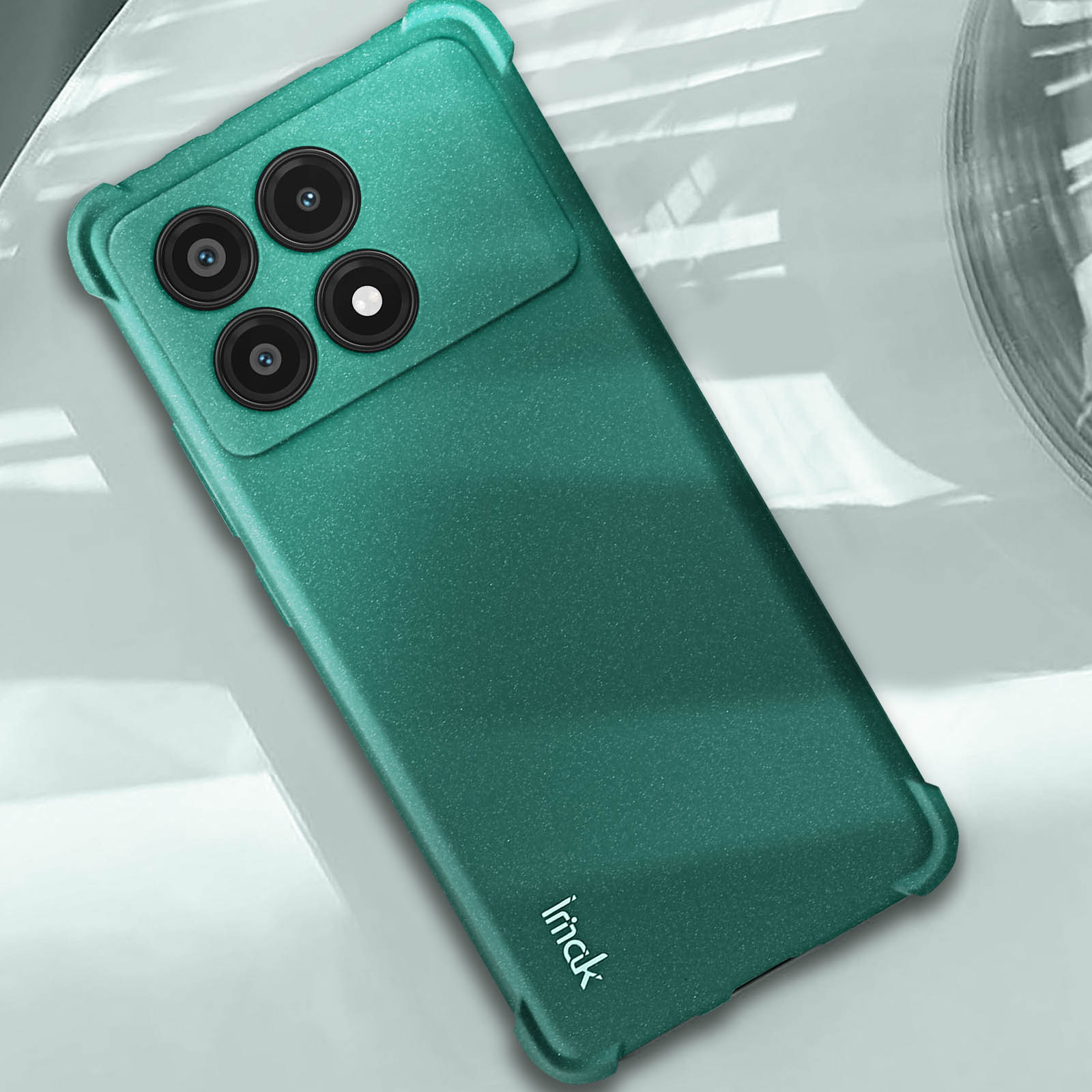Custodia per telefono verde su una superficie bianca. La custodia protegge la fotocamera del telefono. Vista dall'alto.