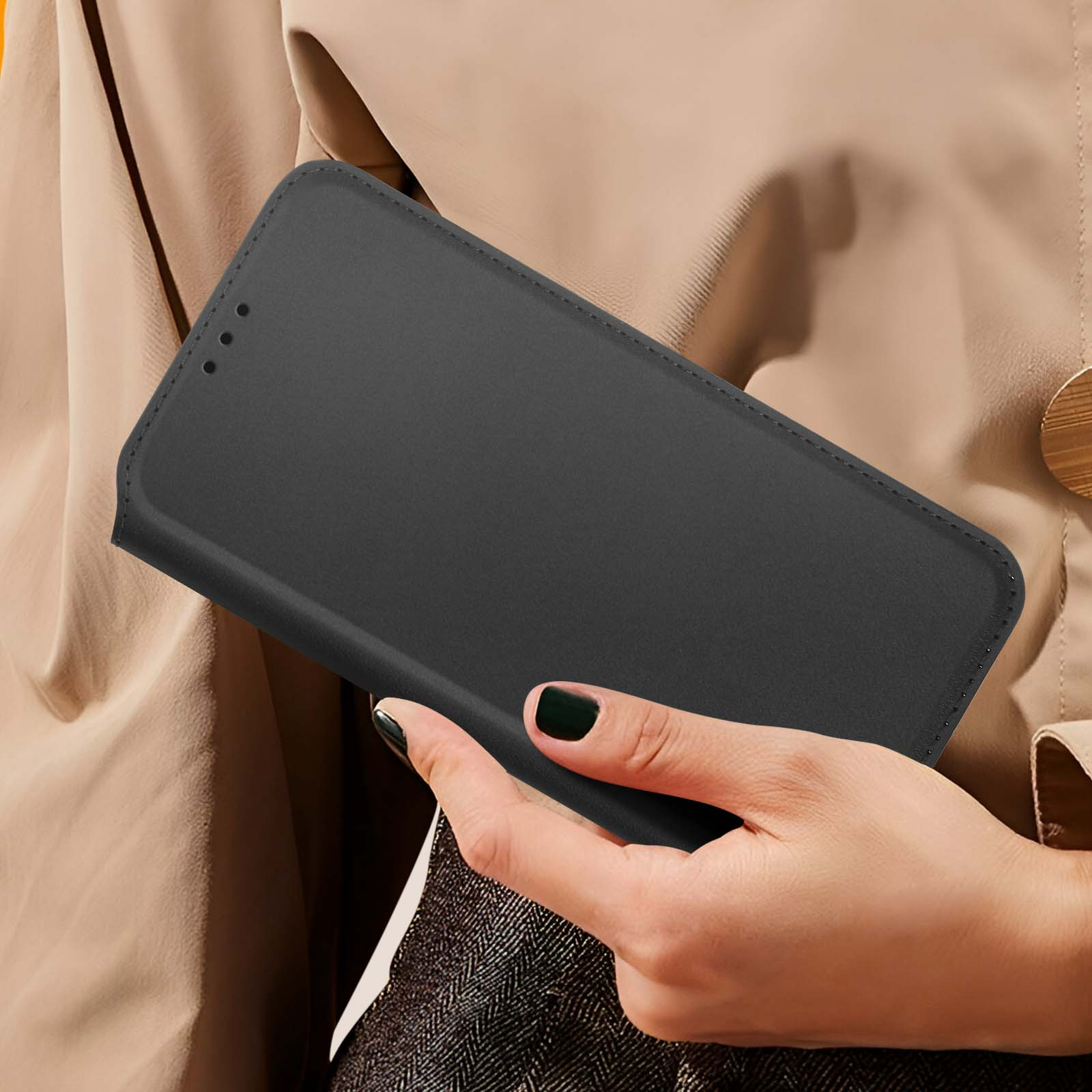 La mano di una donna tiene una custodia per telefono nera e chiusa. La custodia è chiusa.