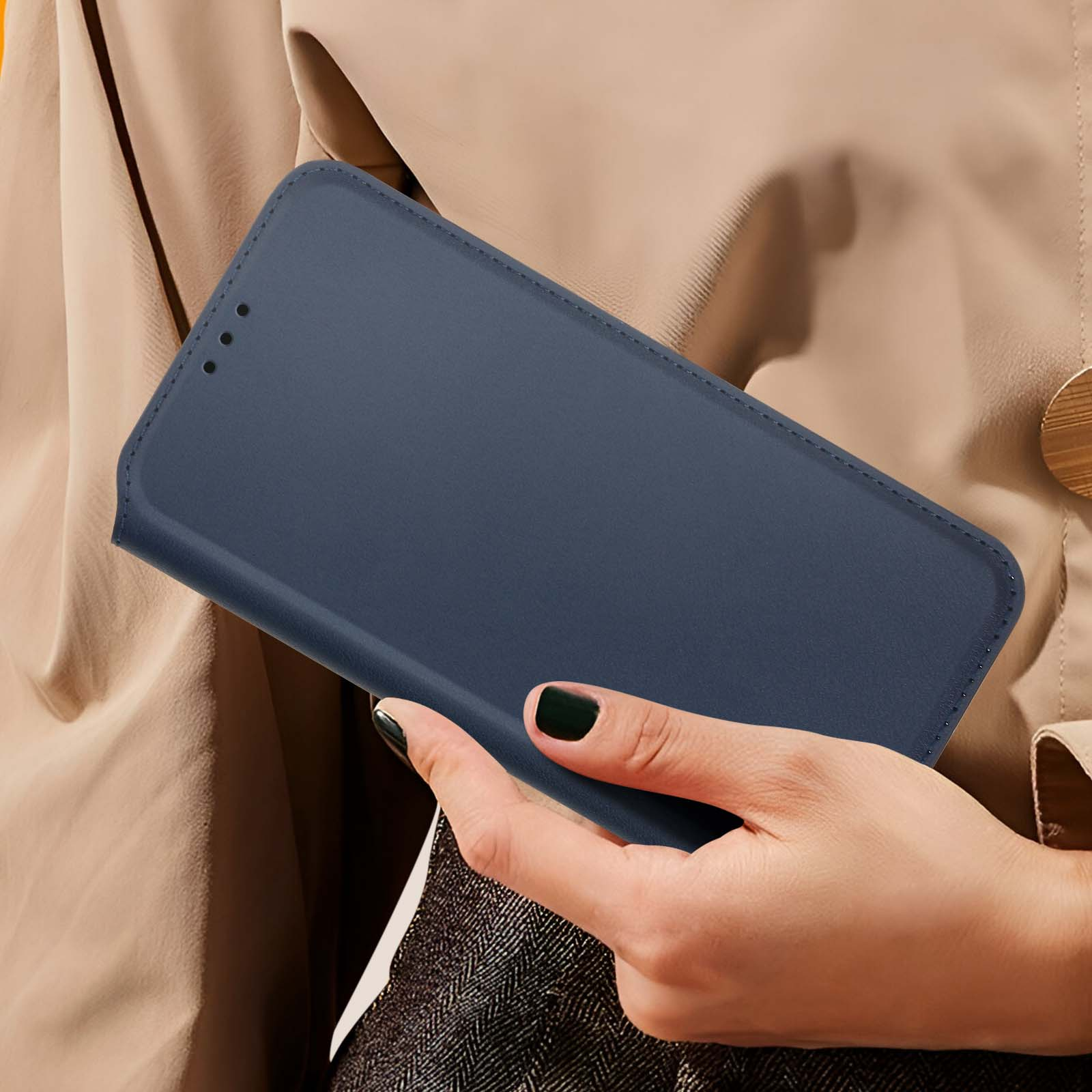 Una donna tiene in mano una custodia blu scuro. La custodia è chiusa. Sfondo beige.