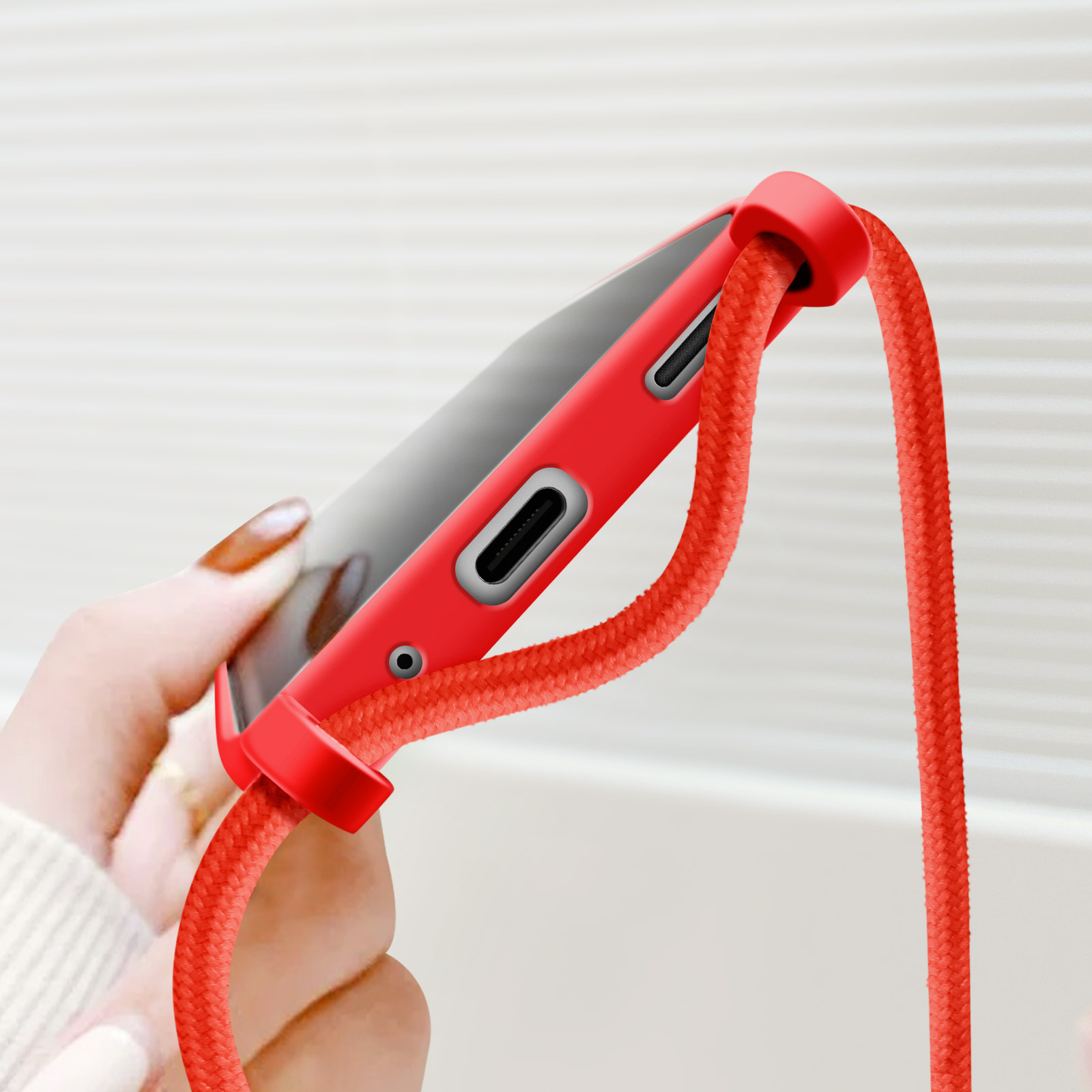 Mano che tiene un telefono rosso con un cordino rosso.