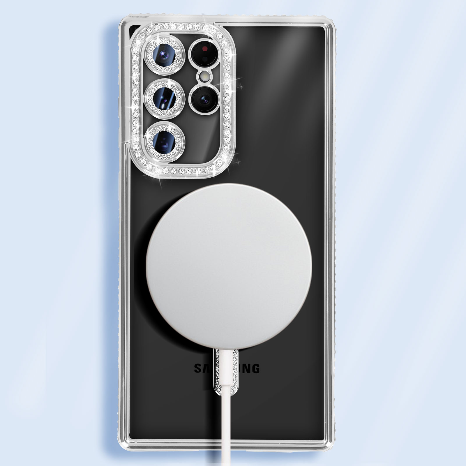 Schwarzes Samsung-Telefon mit klarer Hülle und weißem Ladepad. Kristallakzente auf der Hülle.