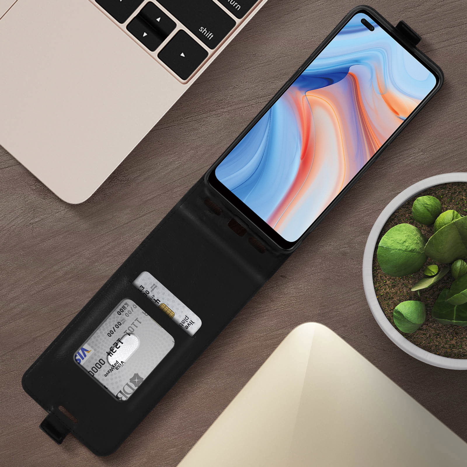Custodia per telefono in pelle nera con due carte all'interno. Un laptop sullo sfondo.