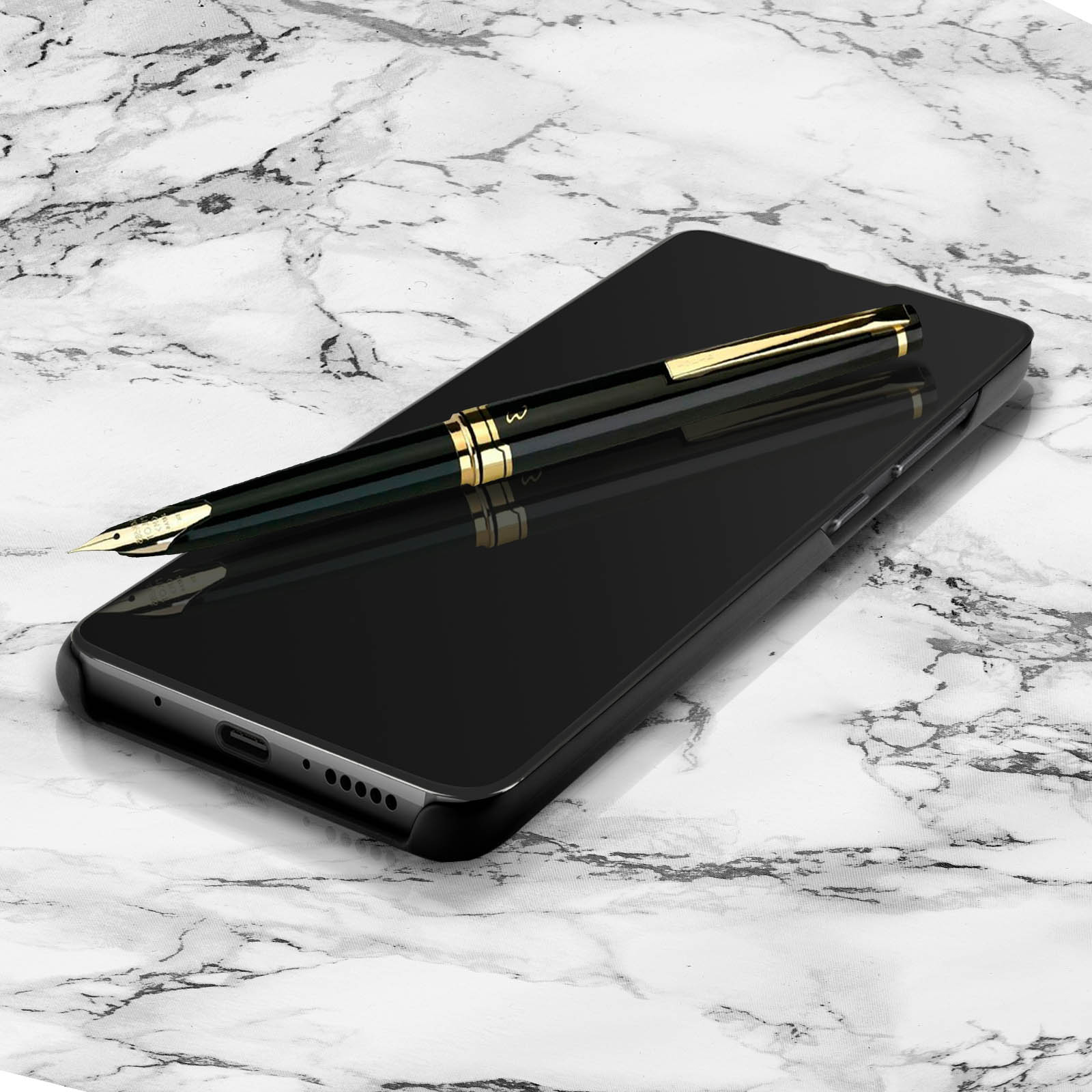 Uno smartphone nero con una penna oro e nera sopra, appoggiato su una superficie di marmo.