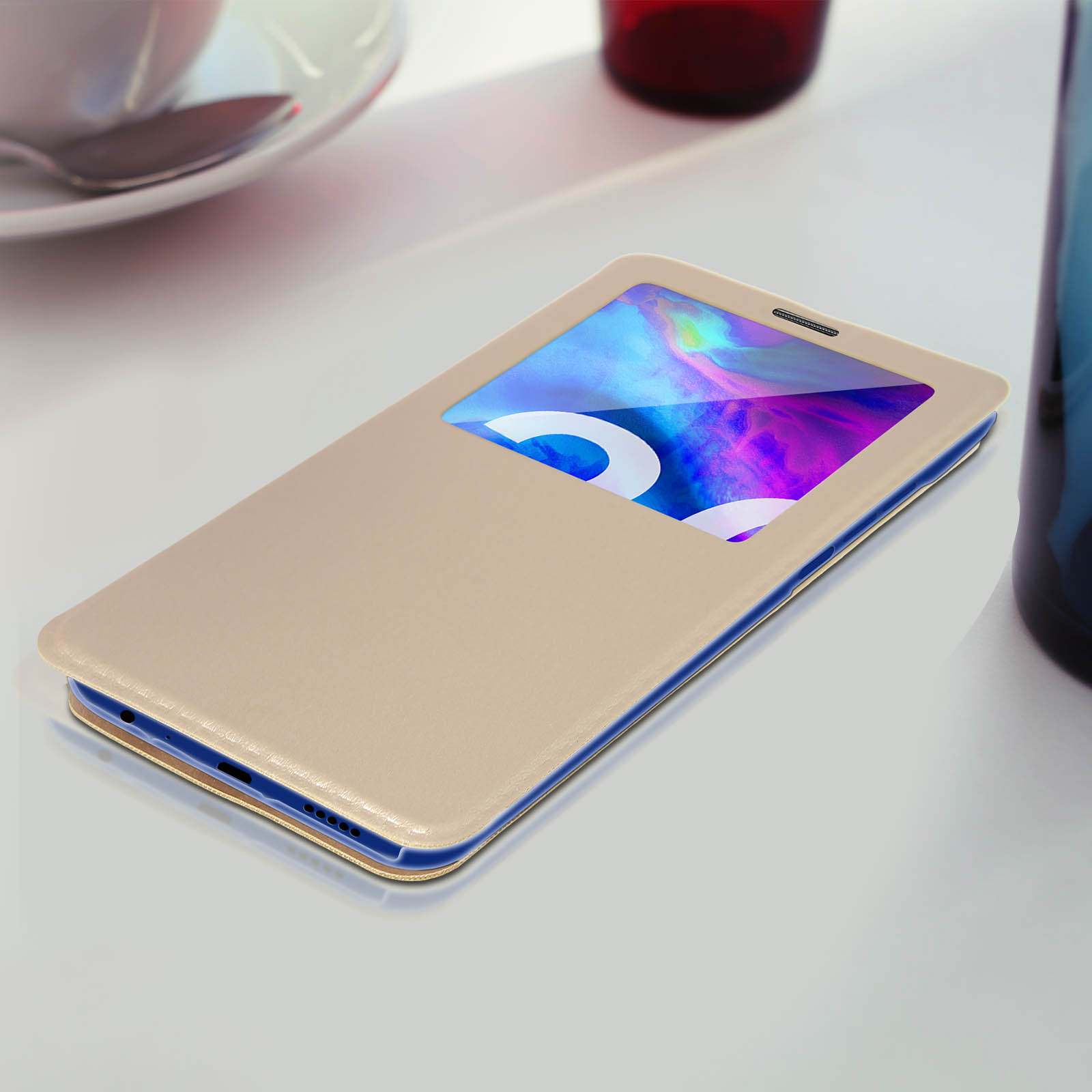 Custodia beige con schermo con immagine colorata. Su superficie bianca, vicino a tazza.