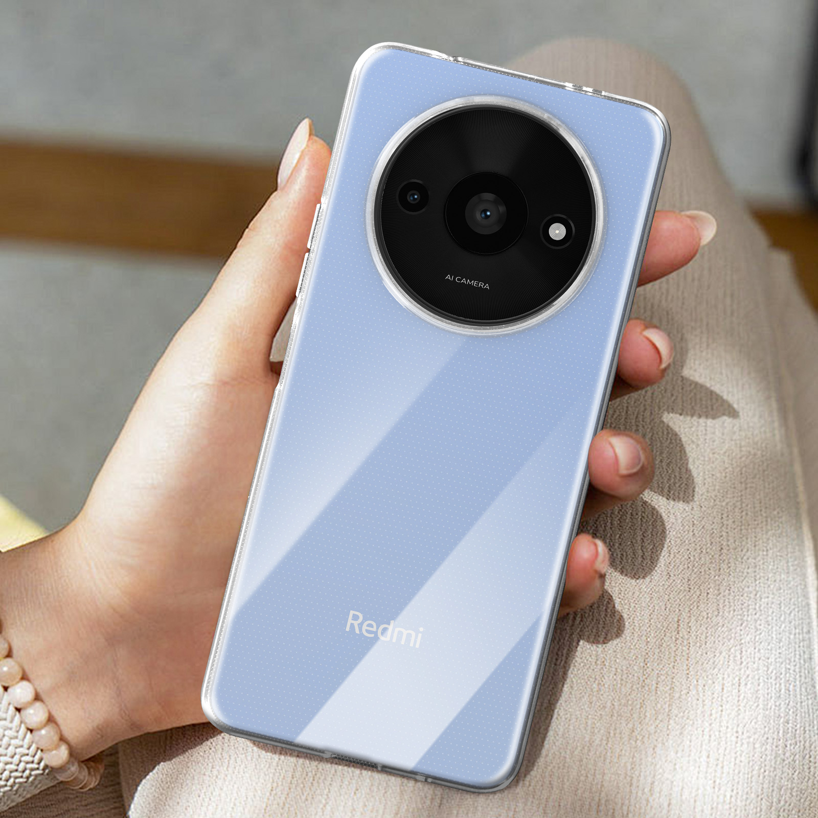Telefono Redmi in custodia trasparente. Obiettivo fotocamera AI, mano che tiene, sfondo blu.