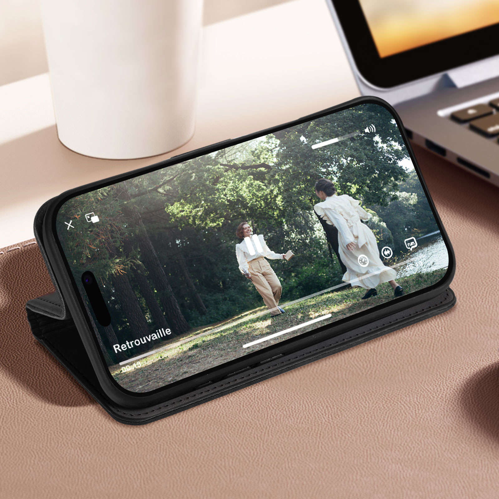 Un telefono in una custodia nera mostra un video di due persone in un parco, su una superficie marrone.