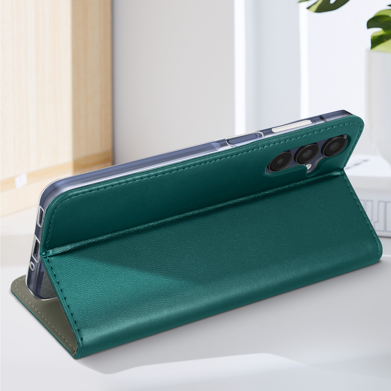 Una custodia verde per telefono tiene un telefono su un tavolo con un libro bianco.