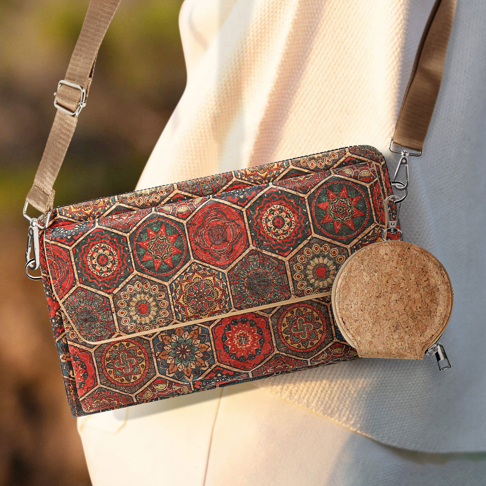 Eine gemusterte Tasche mit einem Korkzubehör hängt an der Schulter einer Person. Die Tasche hat einen braunen Riemen.