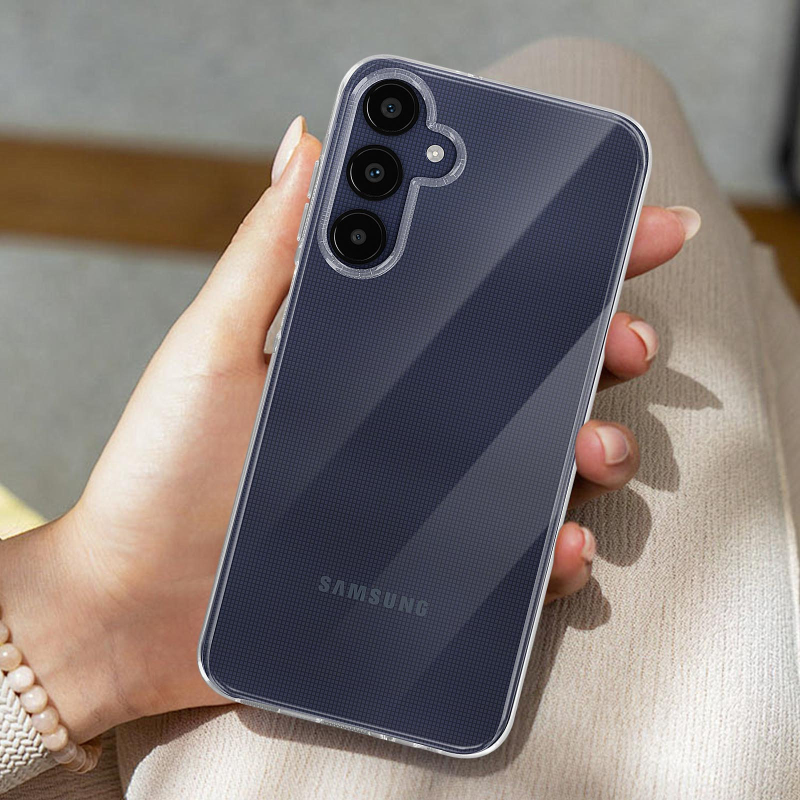 Eine Person hält ein Telefon in einer transparenten Hülle. Das Telefon hat eine Dreifachkamera und das Samsung-Logo.