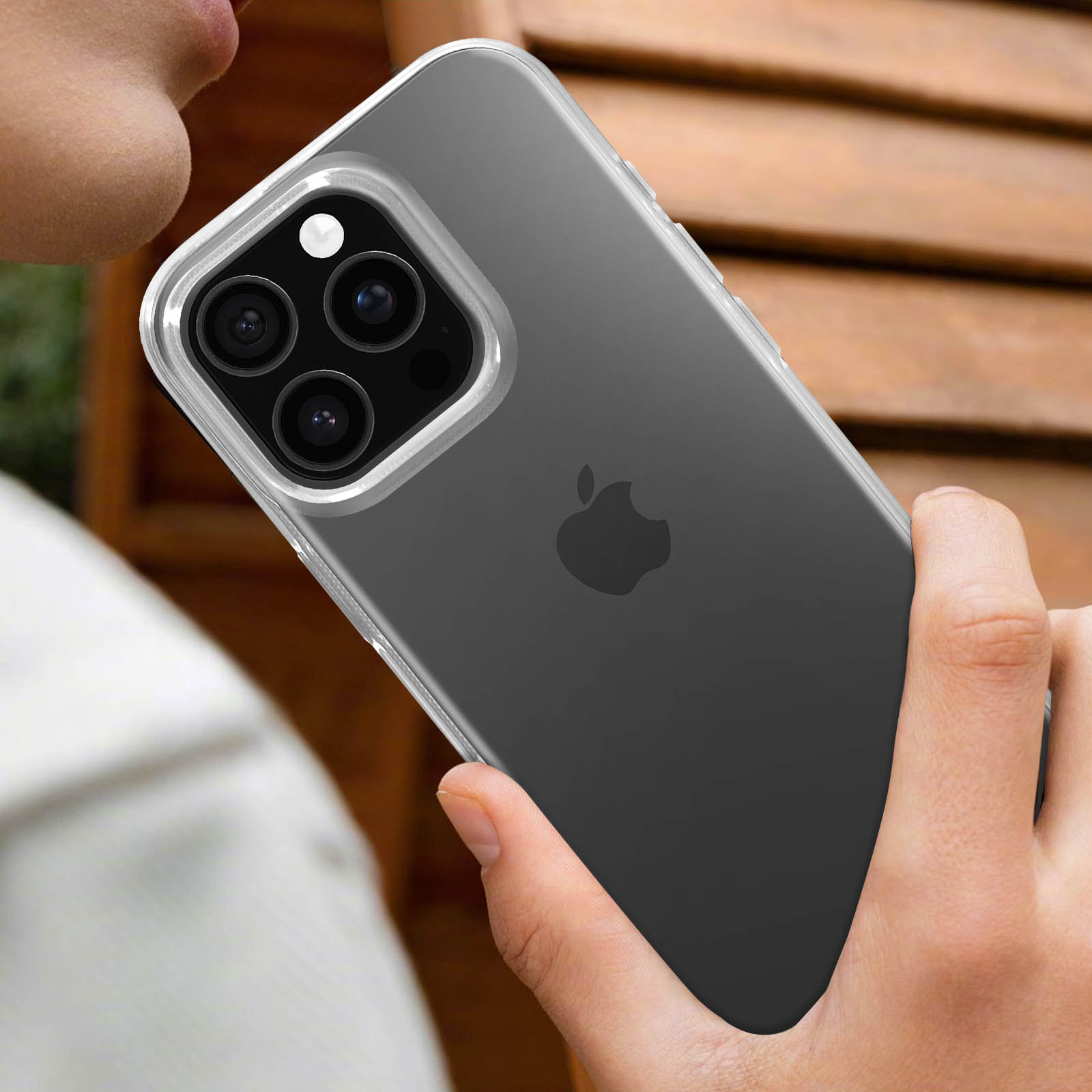 Persona che tiene in mano un telefono con custodia trasparente e logo Apple.