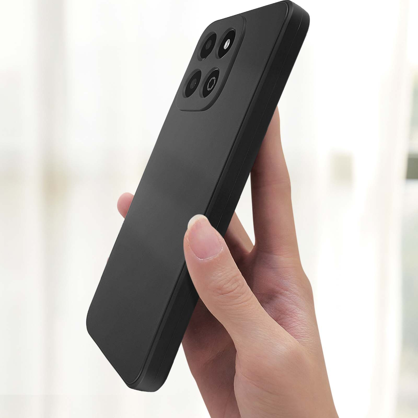 Eine Hand hält ein schwarzes Telefon. Vier Kameras sichtbar. Schwarzer Rahmen.