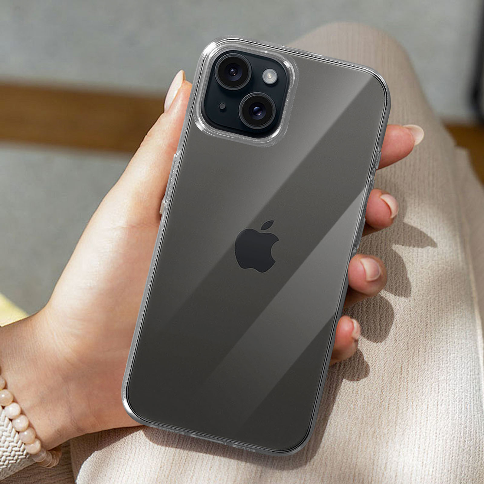 Una mano che tiene un telefono con una custodia trasparente. Il telefono ha il logo Apple.