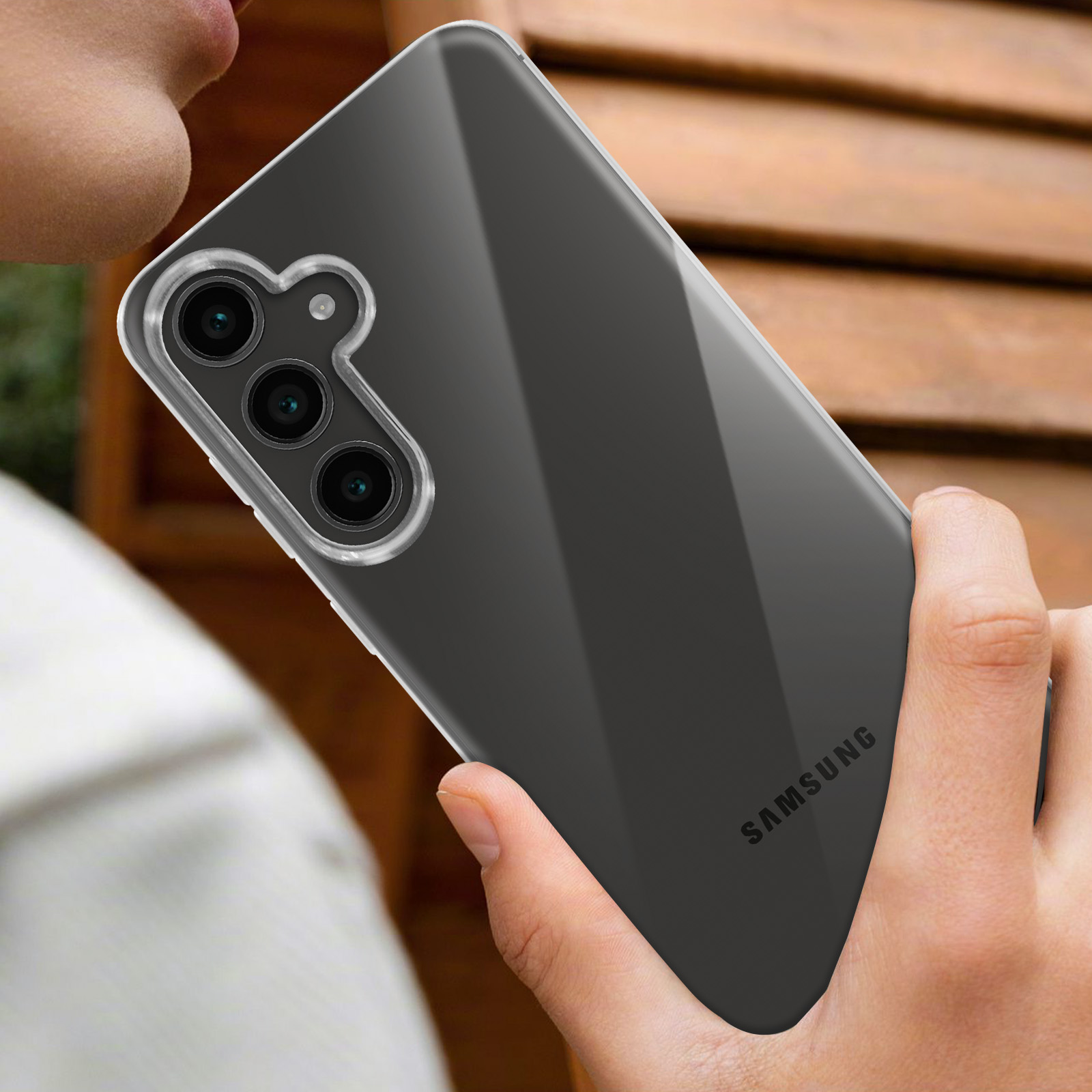 Una mano che tiene un telefono nero con una custodia trasparente. Il telefono ha fotocamere.