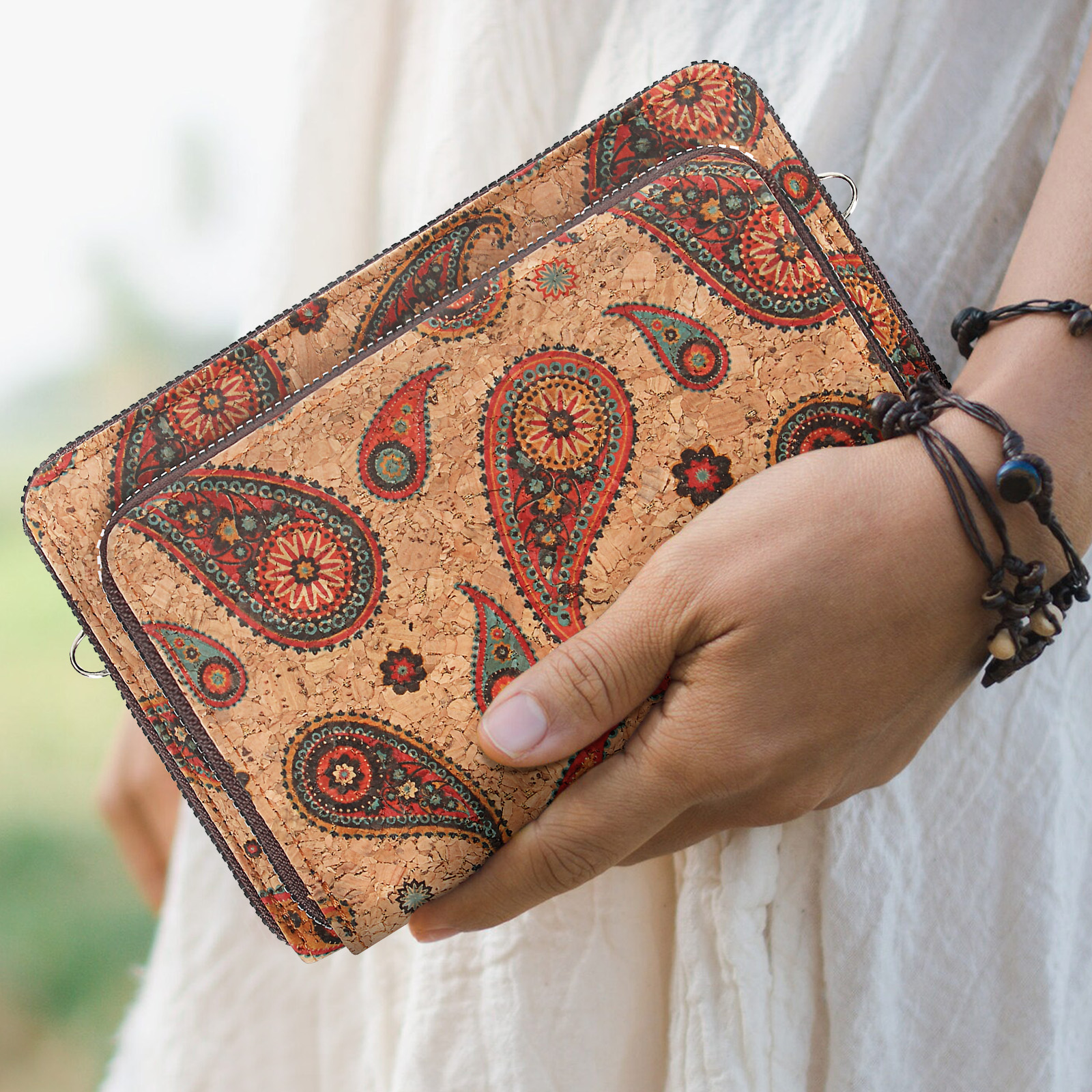 Hand hält Kork-Geldbörse mit Paisley-Muster. Natürlicher Hintergrund.