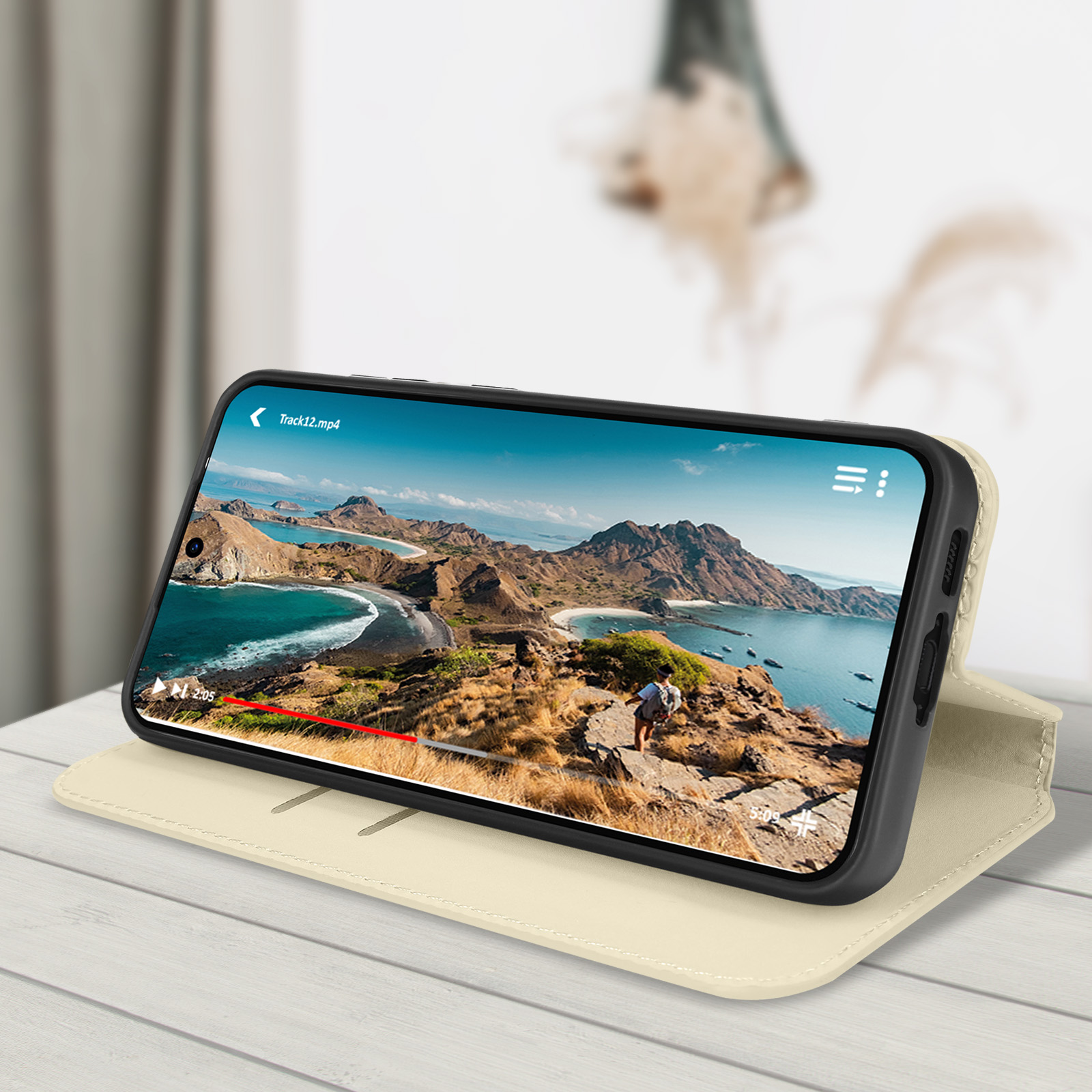 Telefono in custodia su supporto, riproduce un video. Sfondo: montagne e mare.