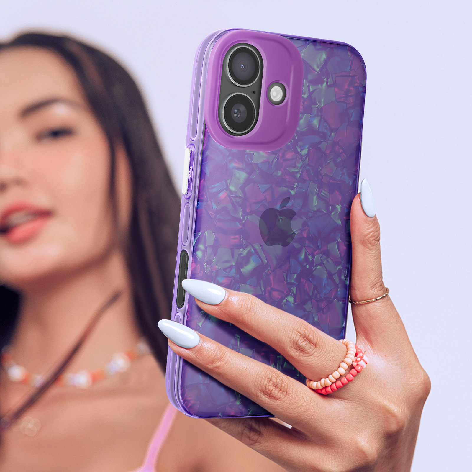 Donna che tiene un telefono con custodia viola iridescente. Anello e braccialetto rosa.