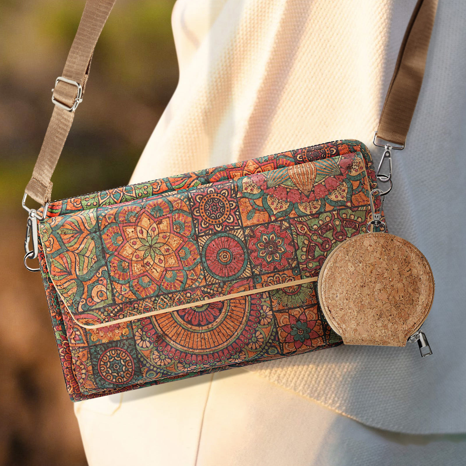 Eine Handtasche mit farbenfrohem Muster und eine kleinere runde Geldbörse mit einem Riemen, die vor weißem Hintergrund hängt.