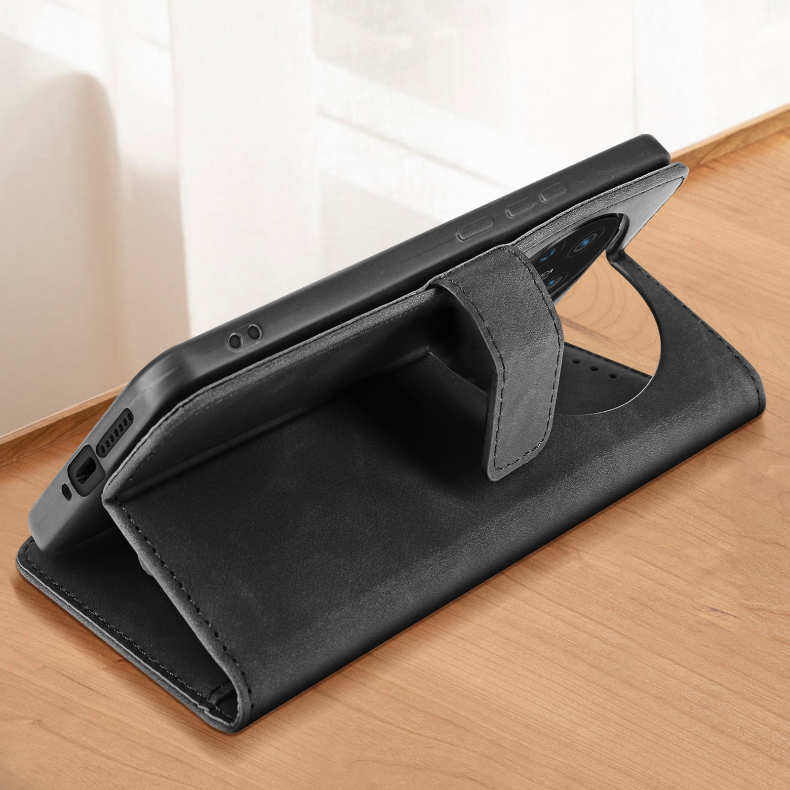 Une coque de téléphone noire ouverte. Téléphone à l'intérieur avec objectif Leica. La coque est sur une table en bois.