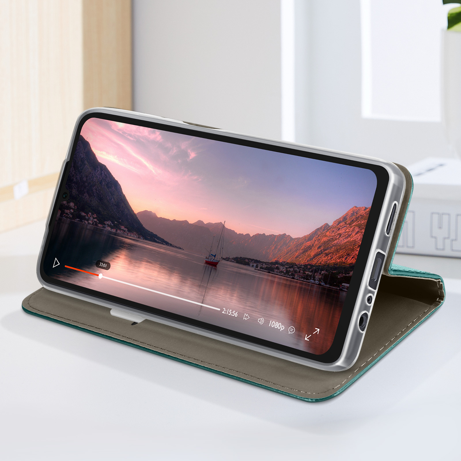 Telefono in custodia verde acqua che mostra un video. Scena con montagne e barca.
