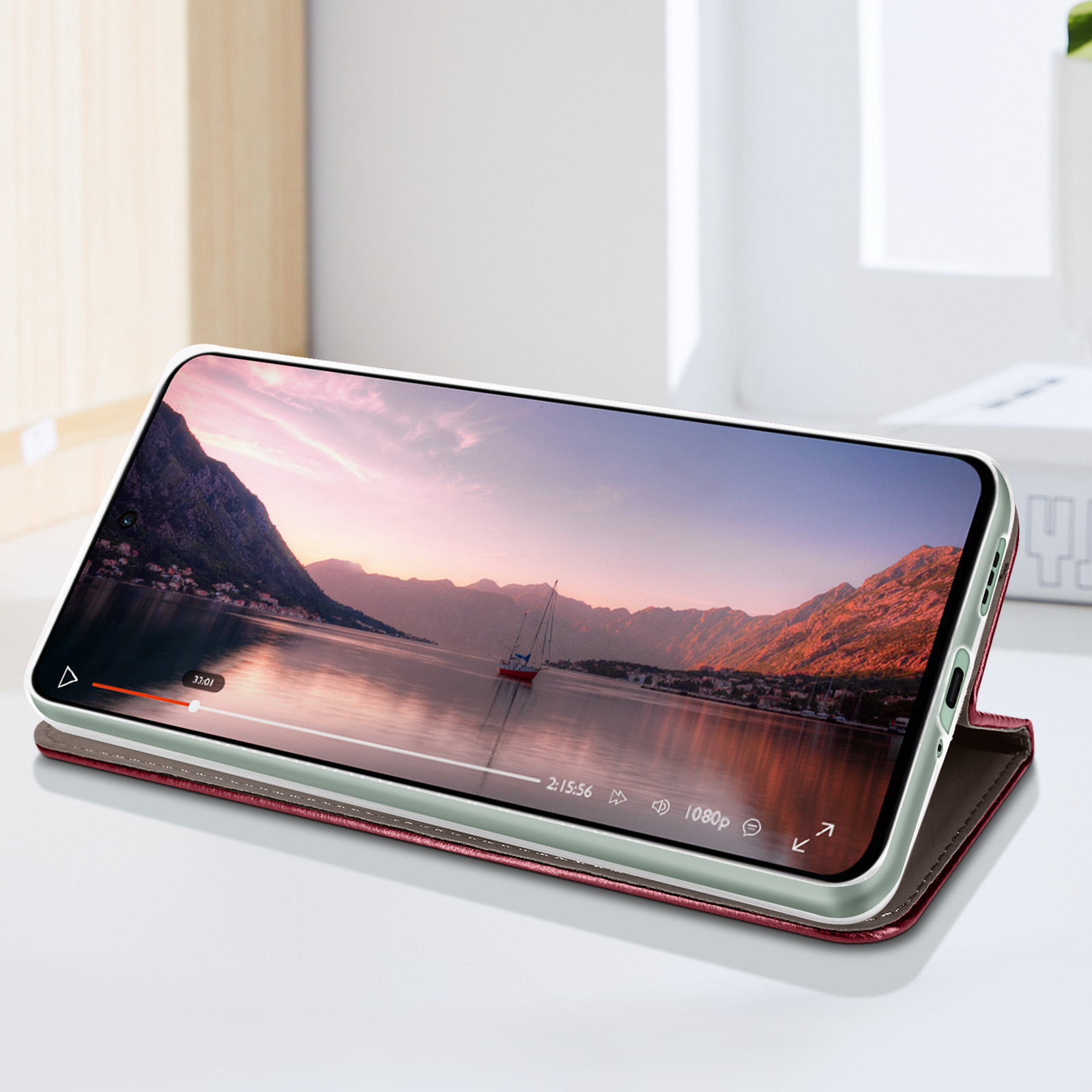 Telefono che mostra una scena del tramonto con una barca, su una superficie.