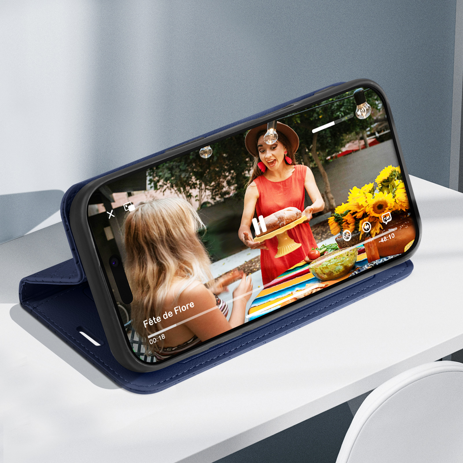 Telefono in custodia blu, mostra un video su un tavolo con cibo.