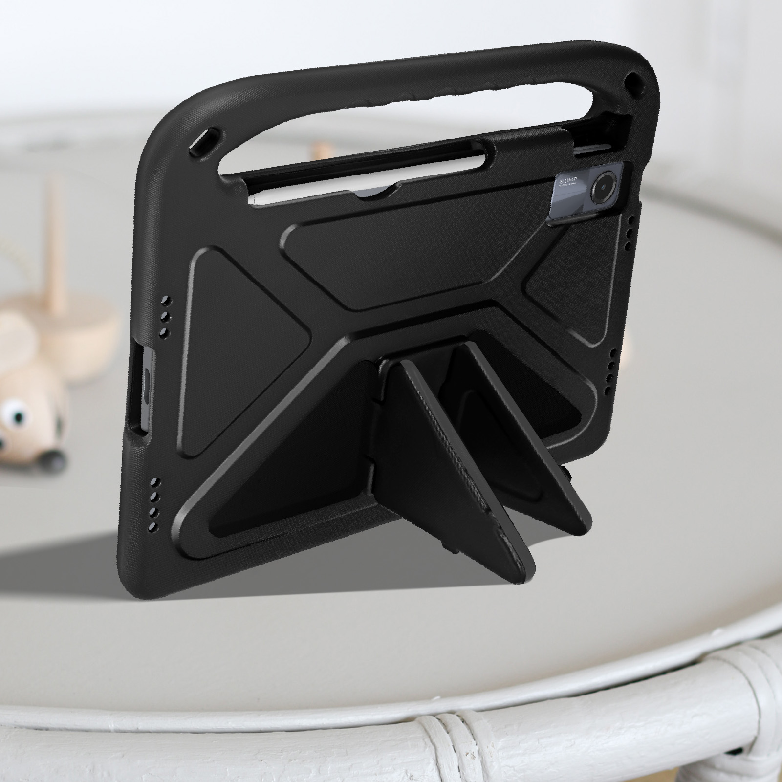 Custodia nera per tablet con supporto, su un tavolo. Un giocattolo a forma di topo è visibile.