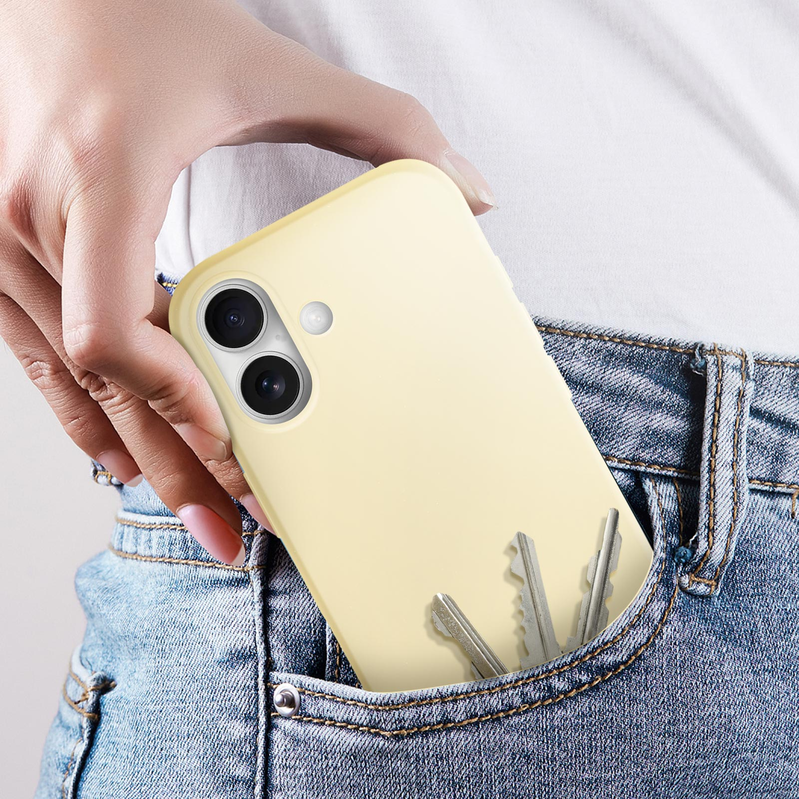 Una custodia per telefono è in una tasca con le chiavi. La custodia è giallo pallido.
