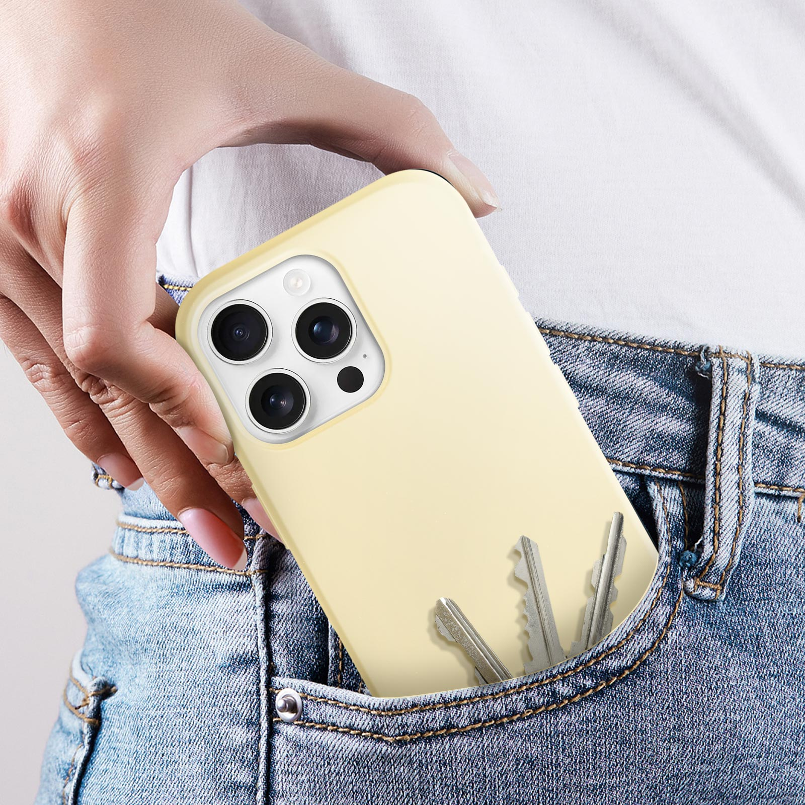 Une main dans une poche de jean tenant un téléphone jaune avec des clés. L'étui est jaune.
