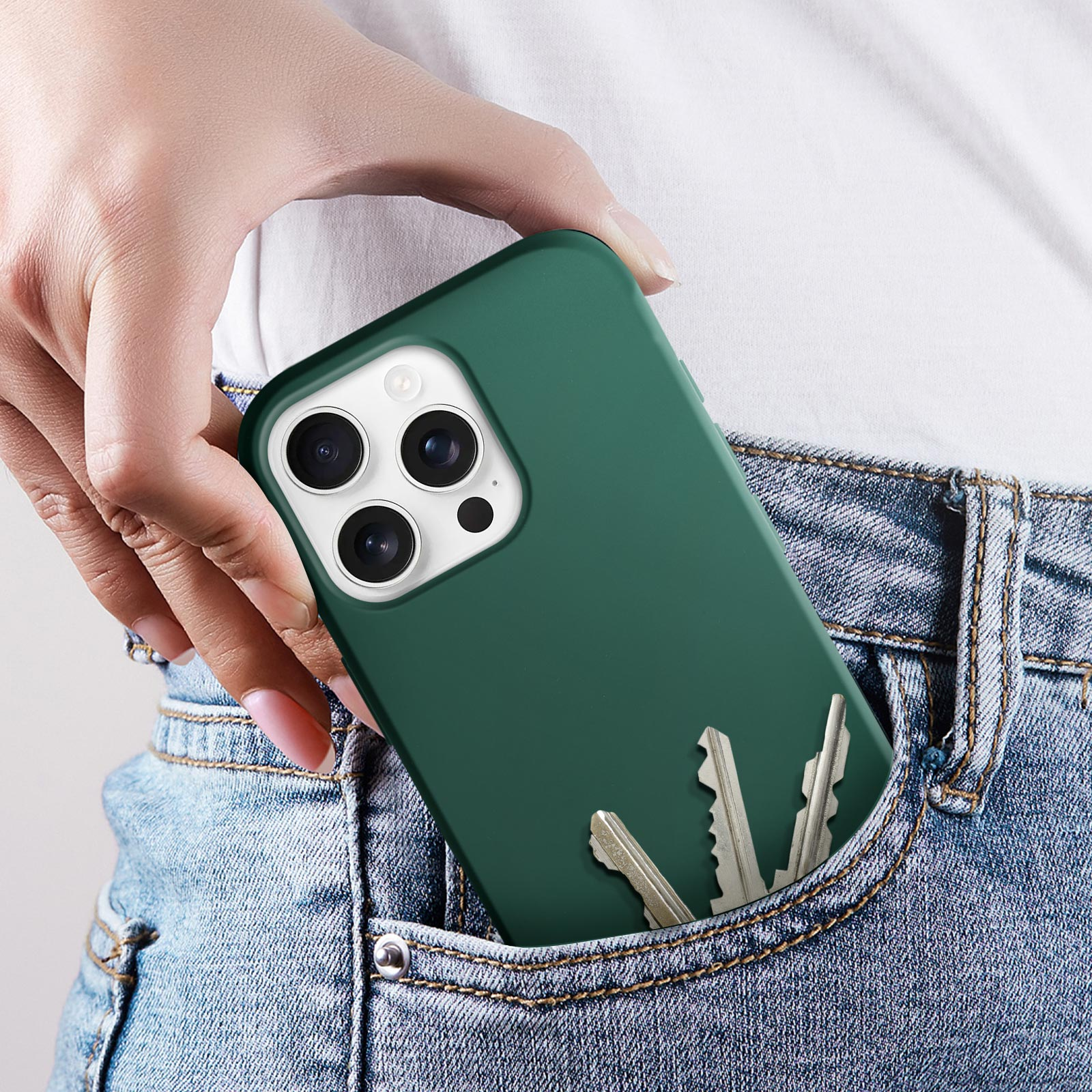 Una mano tiene una custodia verde in una tasca dei jeans con delle chiavi. Sfondo bianco.
