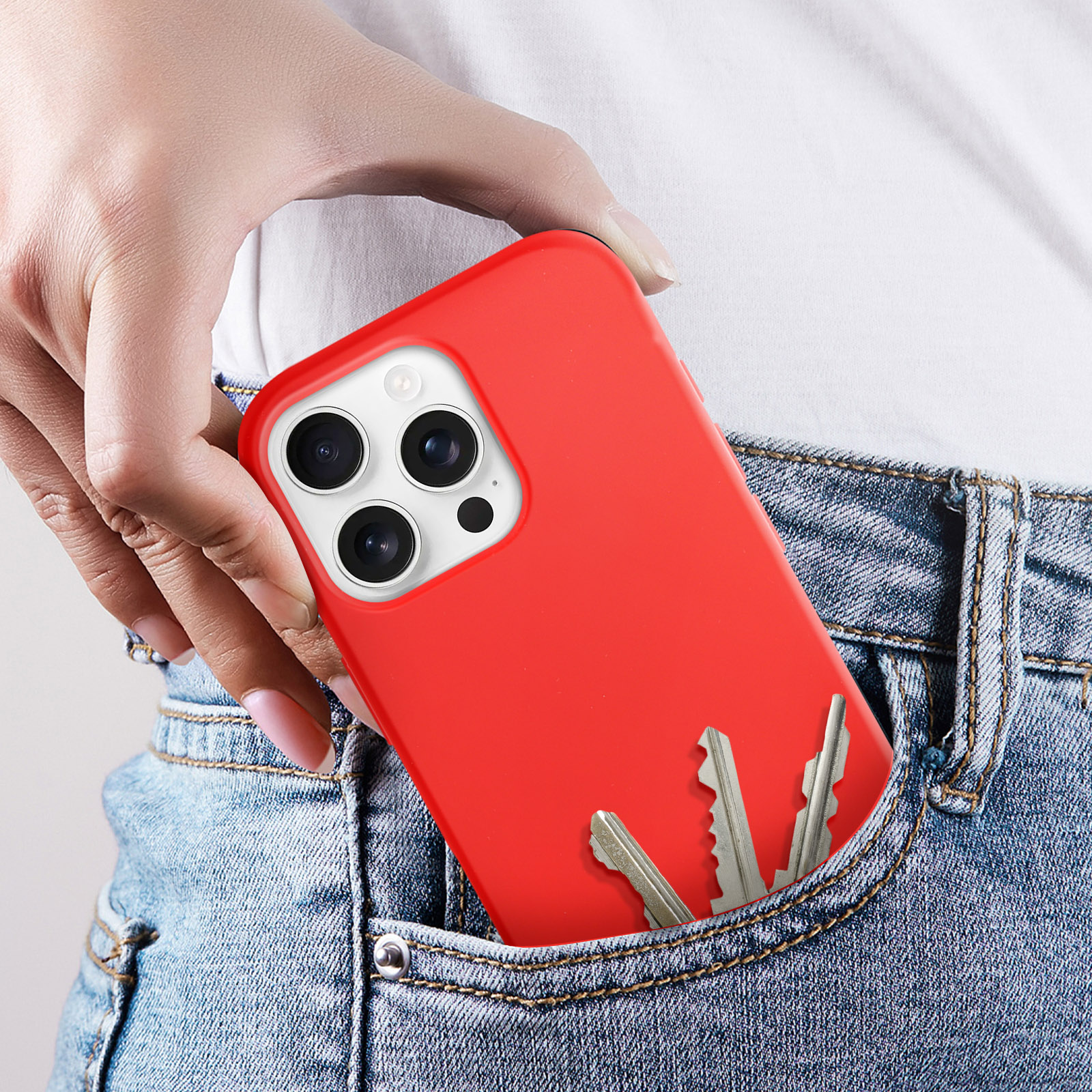 Una custodia rossa per telefono in una tasca dei jeans, con chiavi visibili nella tasca accanto al telefono.