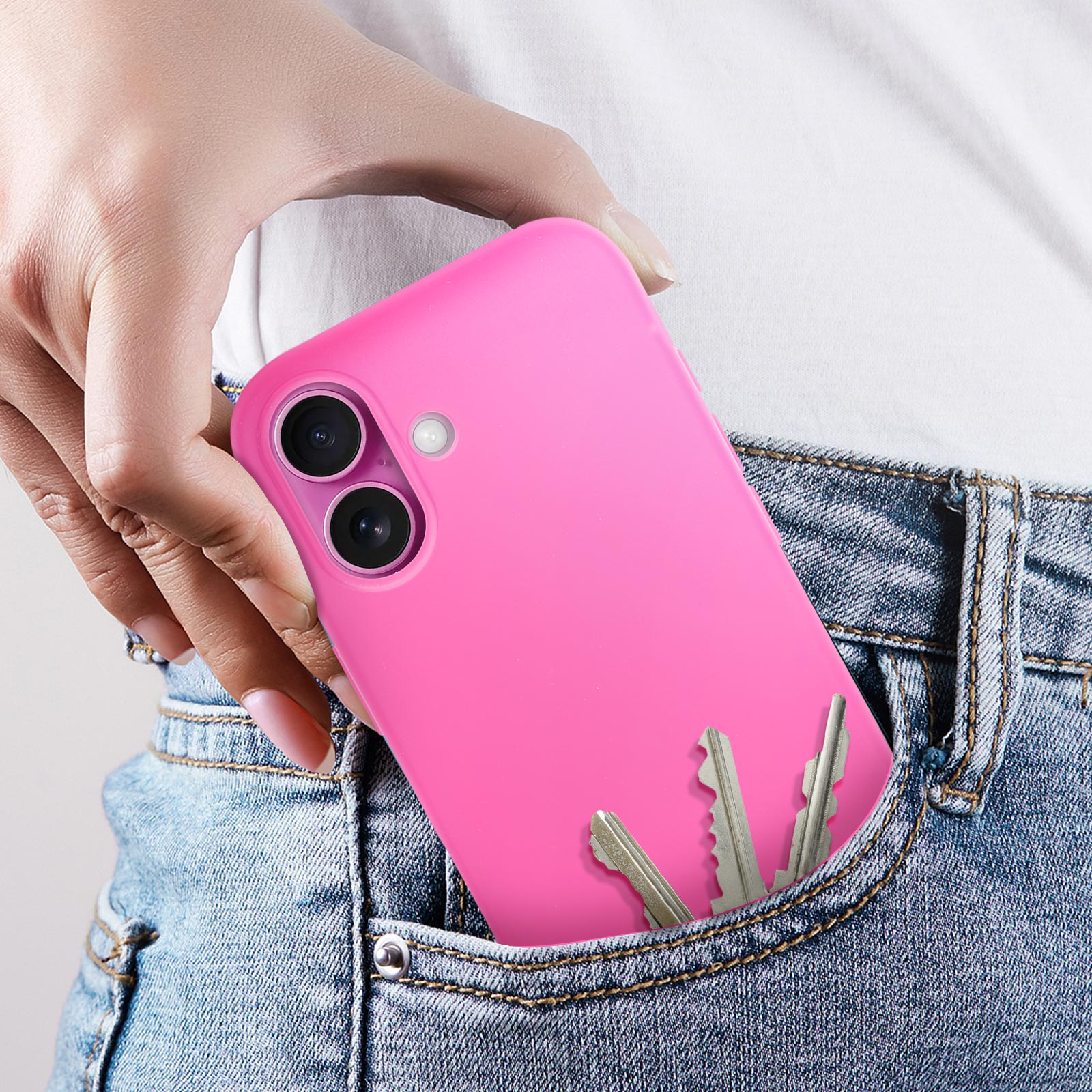 Un telefono rosa in una tasca dei jeans con le chiavi. La mano tiene il telefono.