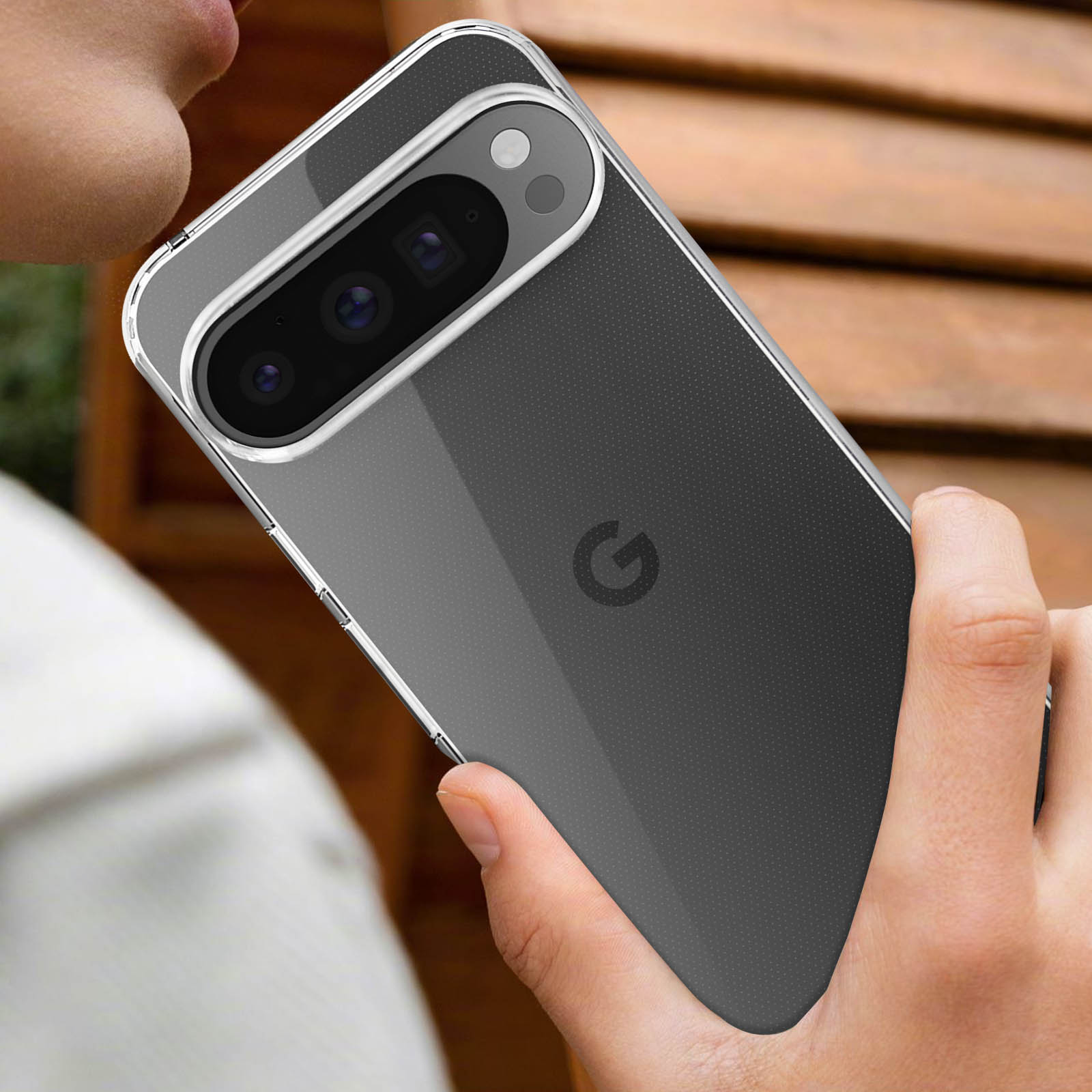 Un telefono in una custodia trasparente tenuto in mano, che mostra l'obiettivo della fotocamera e il retro del telefono.