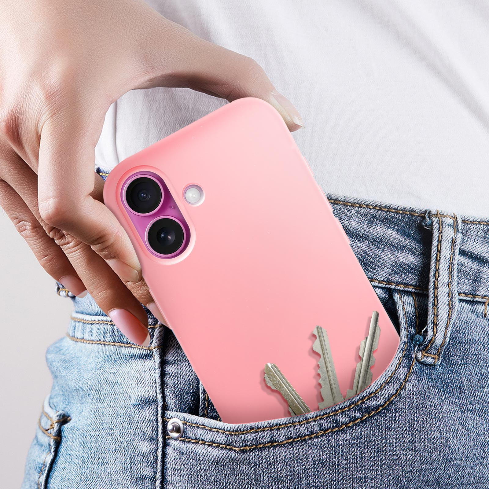 Una mano che mette un telefono con custodia rosa in tasca con le chiavi.