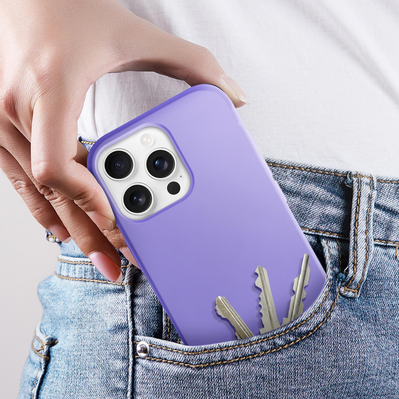 Una mano tiene un telefono viola con chiavi in tasca. La tasca dei jeans è visibile.