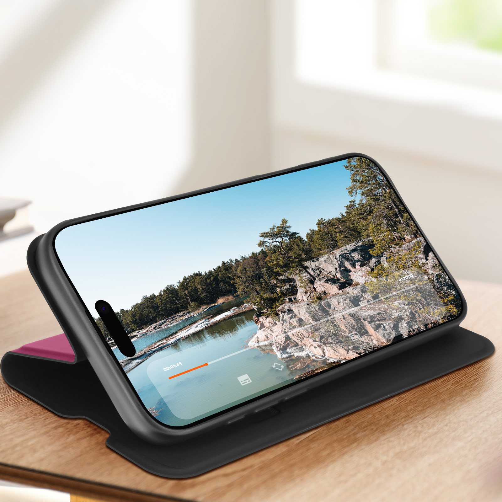 Smartphone in una custodia che mostra un paesaggio di lago e foresta. La custodia è nera e rosa. La scena è all'aperto.
