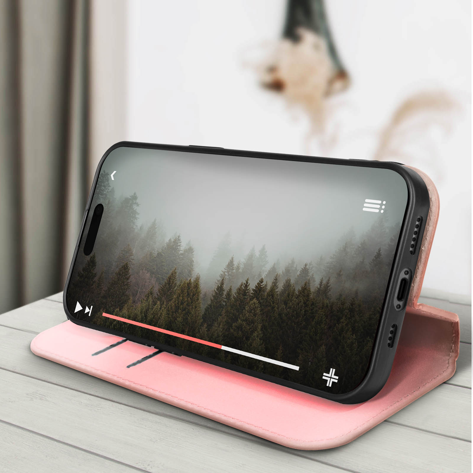 Smartphone in una custodia che riproduce un video di una scena di foresta. La custodia è rosa, su un tavolo di legno.