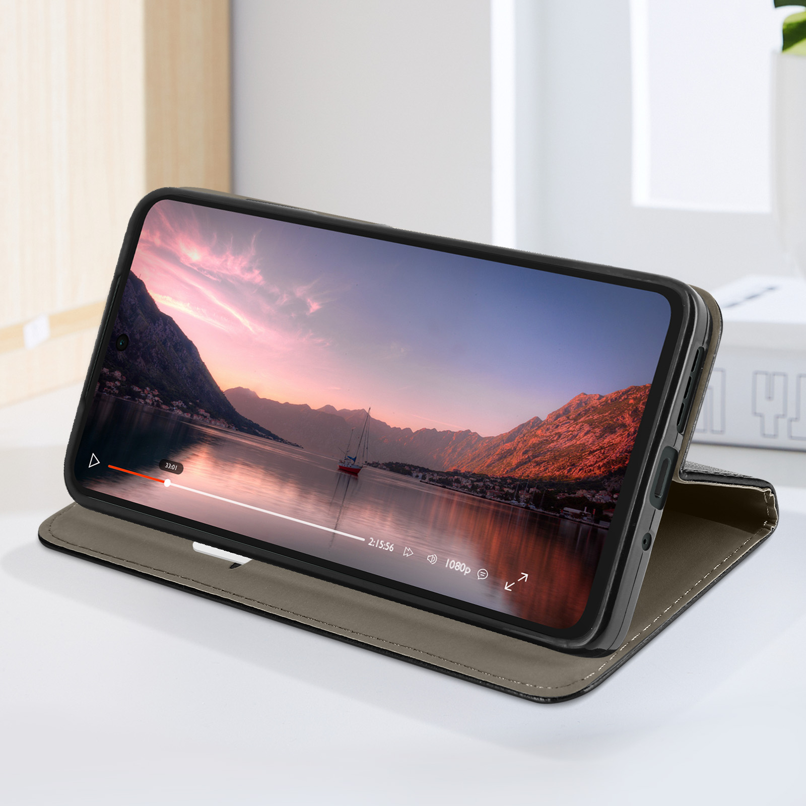 Smartphone in una custodia che mostra un paesaggio di lago e montagna con un tramonto. La custodia è grigia e la superficie bianca.