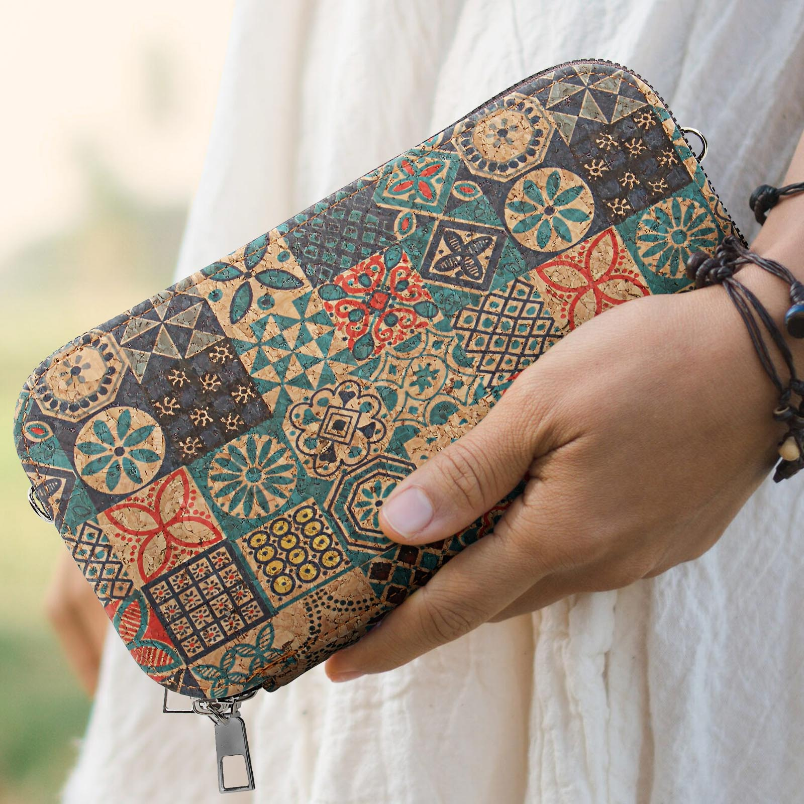 Hand hält eine gemusterte Geldbörse. Die Geldbörse hat ein Patchwork aus geometrischen und floralen Designs.
