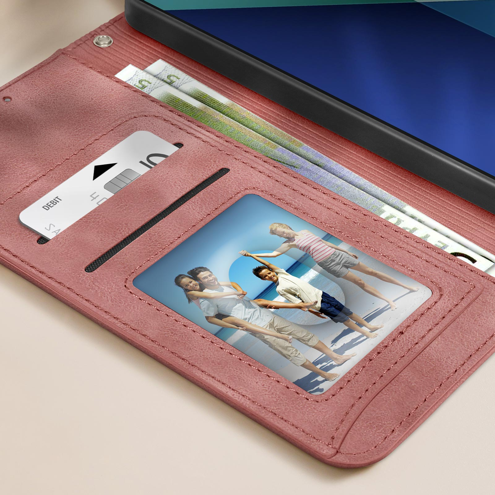 Una custodia rosa per telefono aperta, che mostra una foto di famiglia, una carta di credito e denaro.