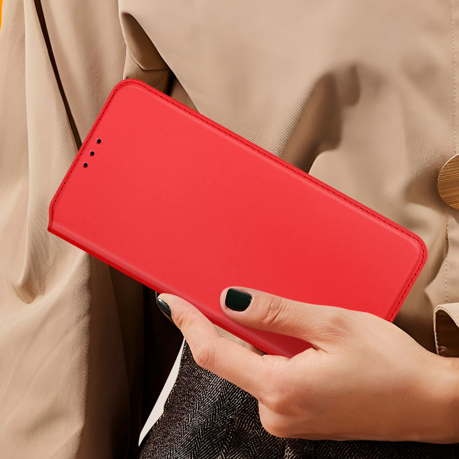 Mano che tiene una custodia per telefono rossa. La custodia è chiusa. Lo sfondo è un cappotto beige.