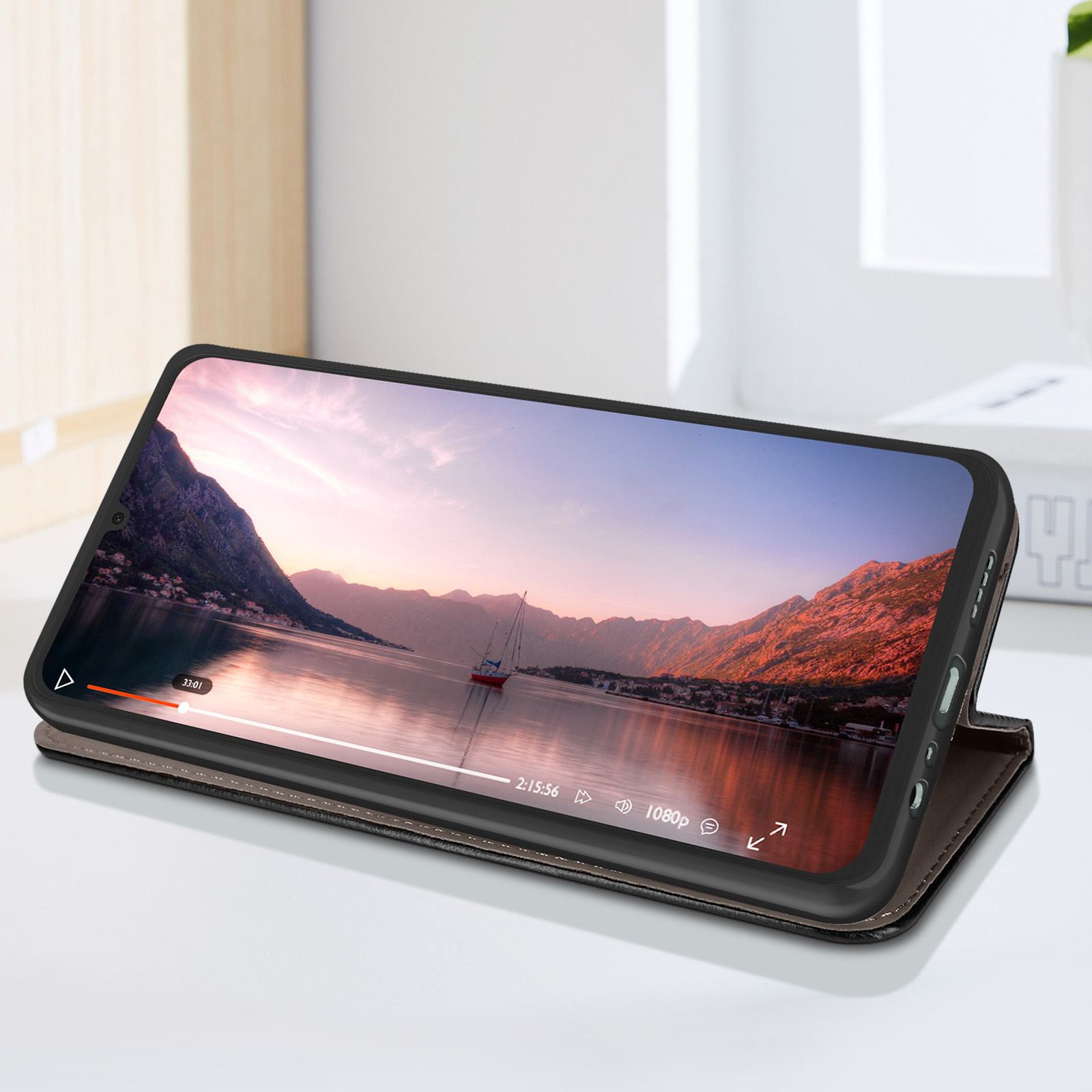 Telefono in custodia appoggiato, riproduce un video. Lo sfondo mostra un lago e montagne.