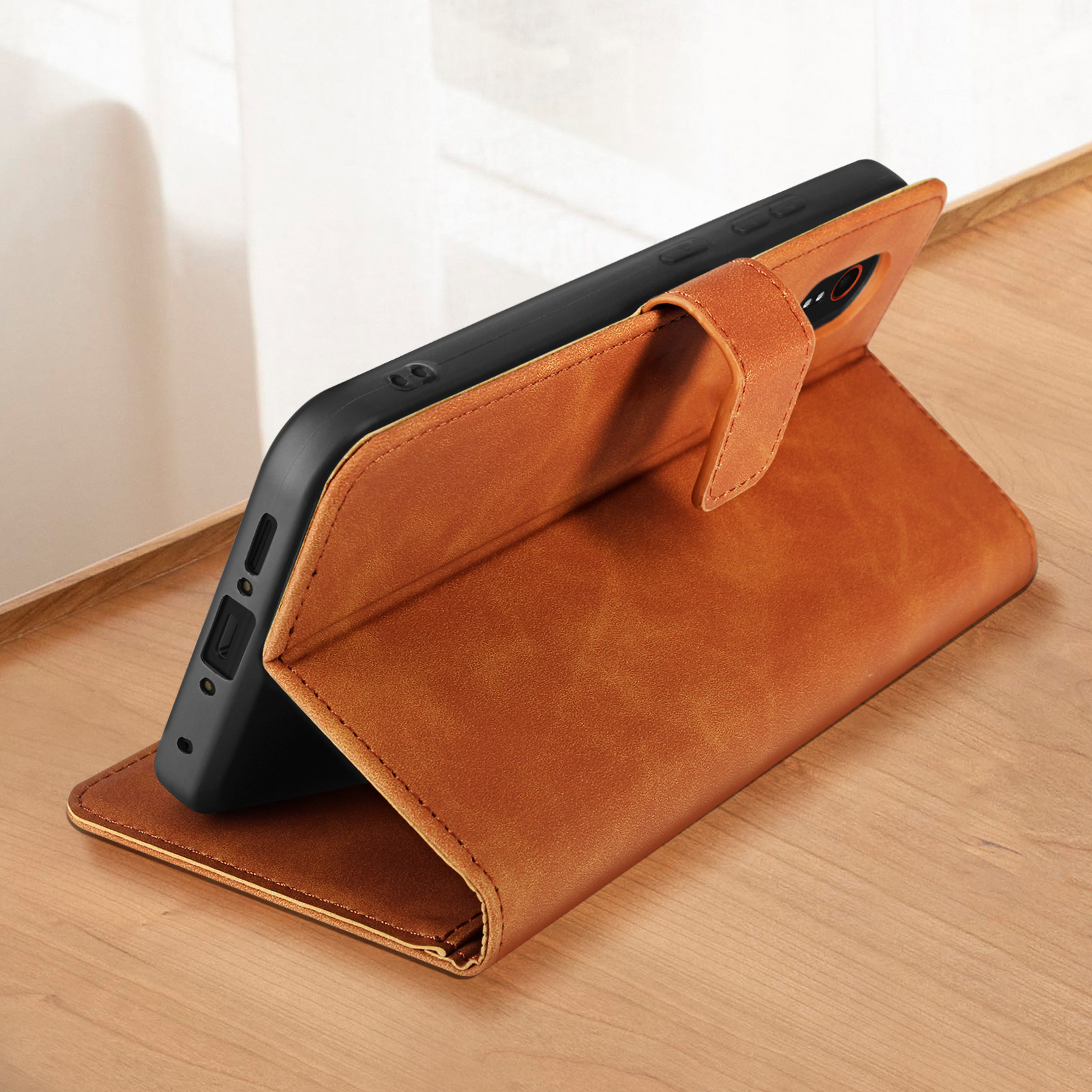 Eine braune Leder-Handyhülle, geöffnet, zeigt ein Telefon im Inneren. Es befindet sich auf einer Holzoberfläche.