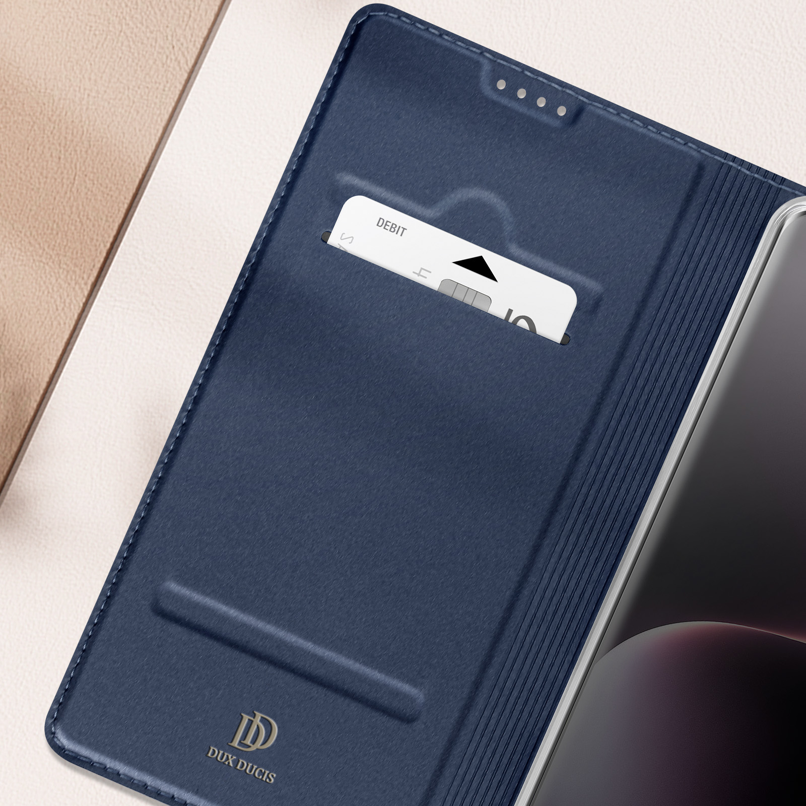 Custodia in pelle blu aperta, che rivela una carta e un telefono. La custodia ha un logo Dux Ducis.