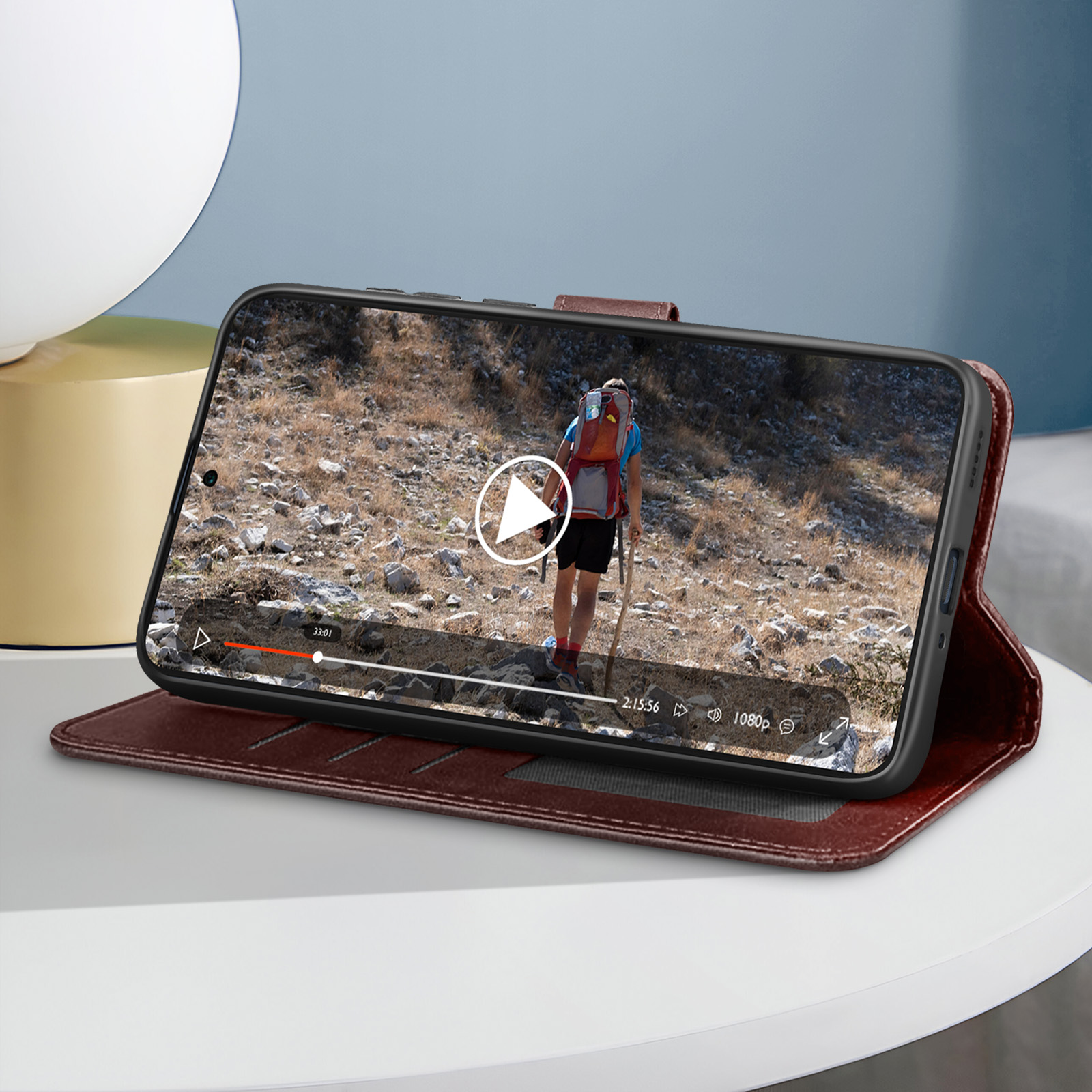Un telefono in una custodia di pelle marrone, aperto su un tavolo, che mostra un video in riproduzione sullo schermo.