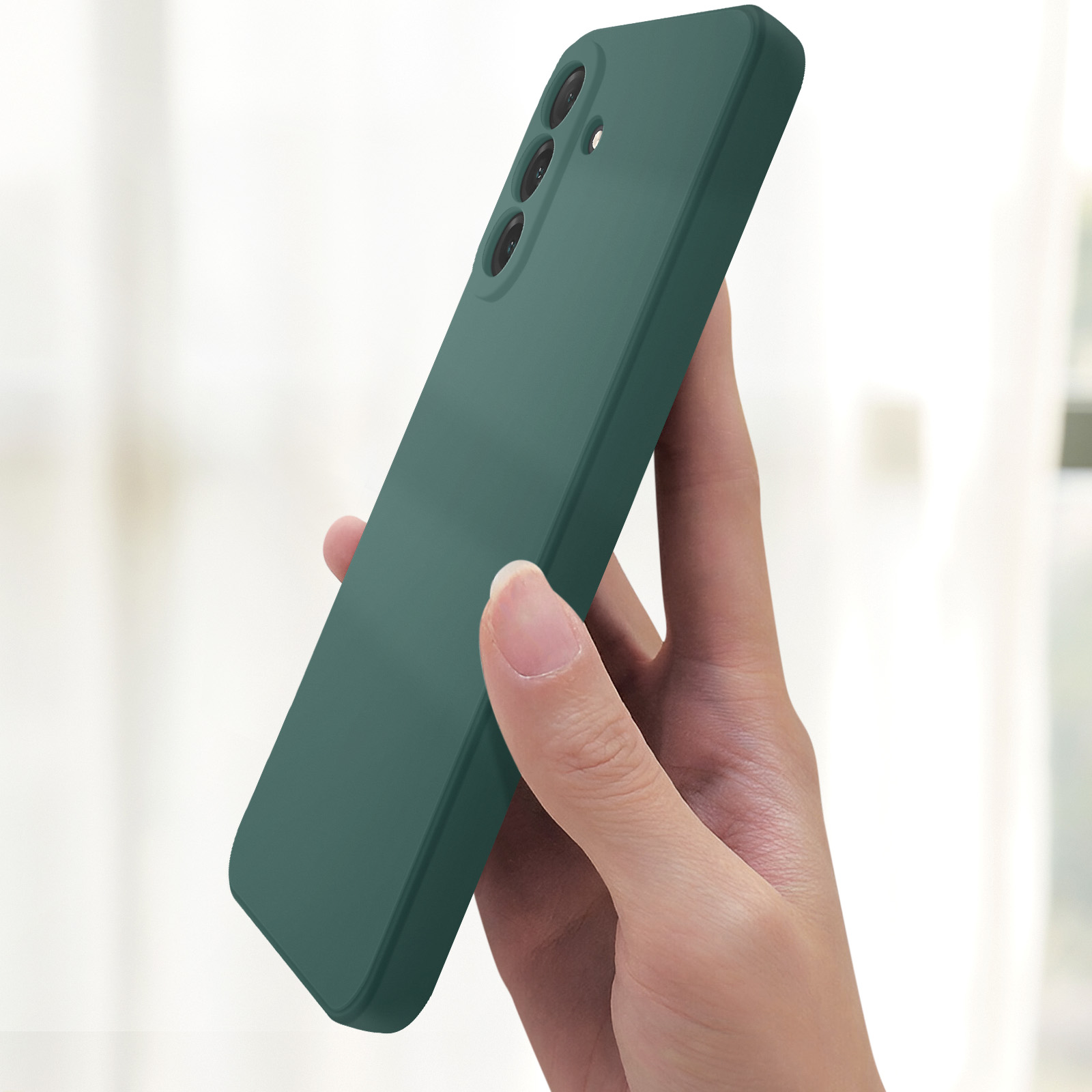 Una custodia verde per telefono tenuta in mano. La custodia ha una tripla fotocamera. Sfondo sfocato.