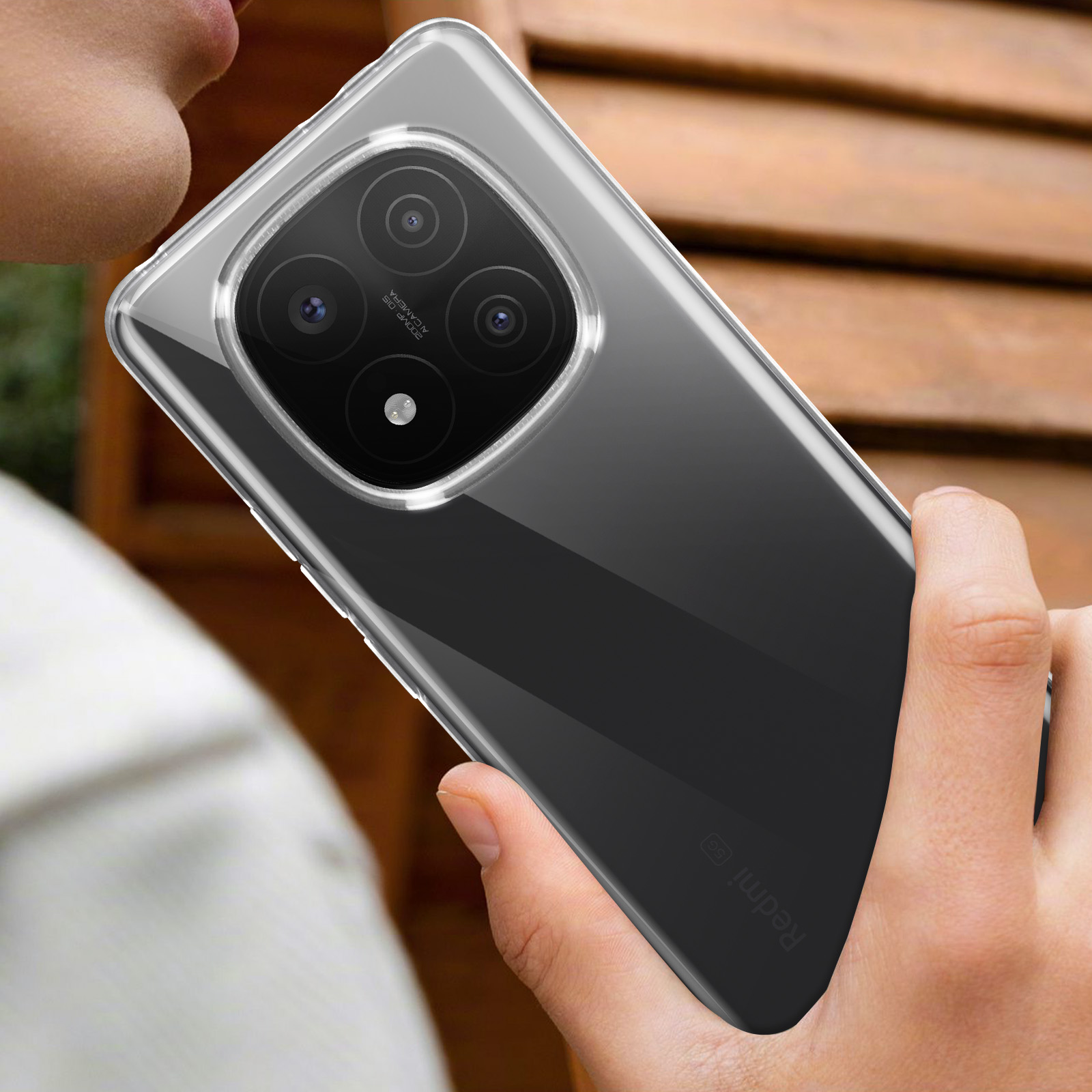 Una mano tiene in mano una custodia trasparente per telefono con un telefono all'interno, il telefono ha una fotocamera.