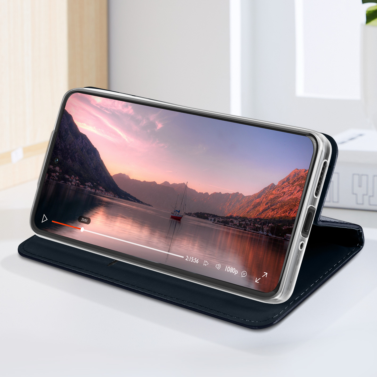 Téléphone sur un support, lisant une vidéo d'un bateau sur un lac. Étui bleu foncé.